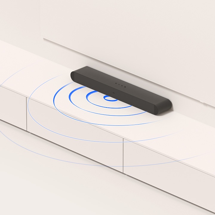 We zien een afbeelding van een soundbar-opstelling. De soundbar staat op een meubel onder de TV. Er komen geluidsgolven uit de onderkant.