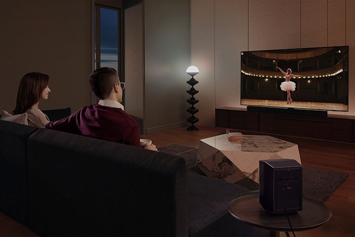 Een stel geniet van een filmavond in hun woonkamer met het theaterachtige surroundgeluid van de Samsung Soundbar.