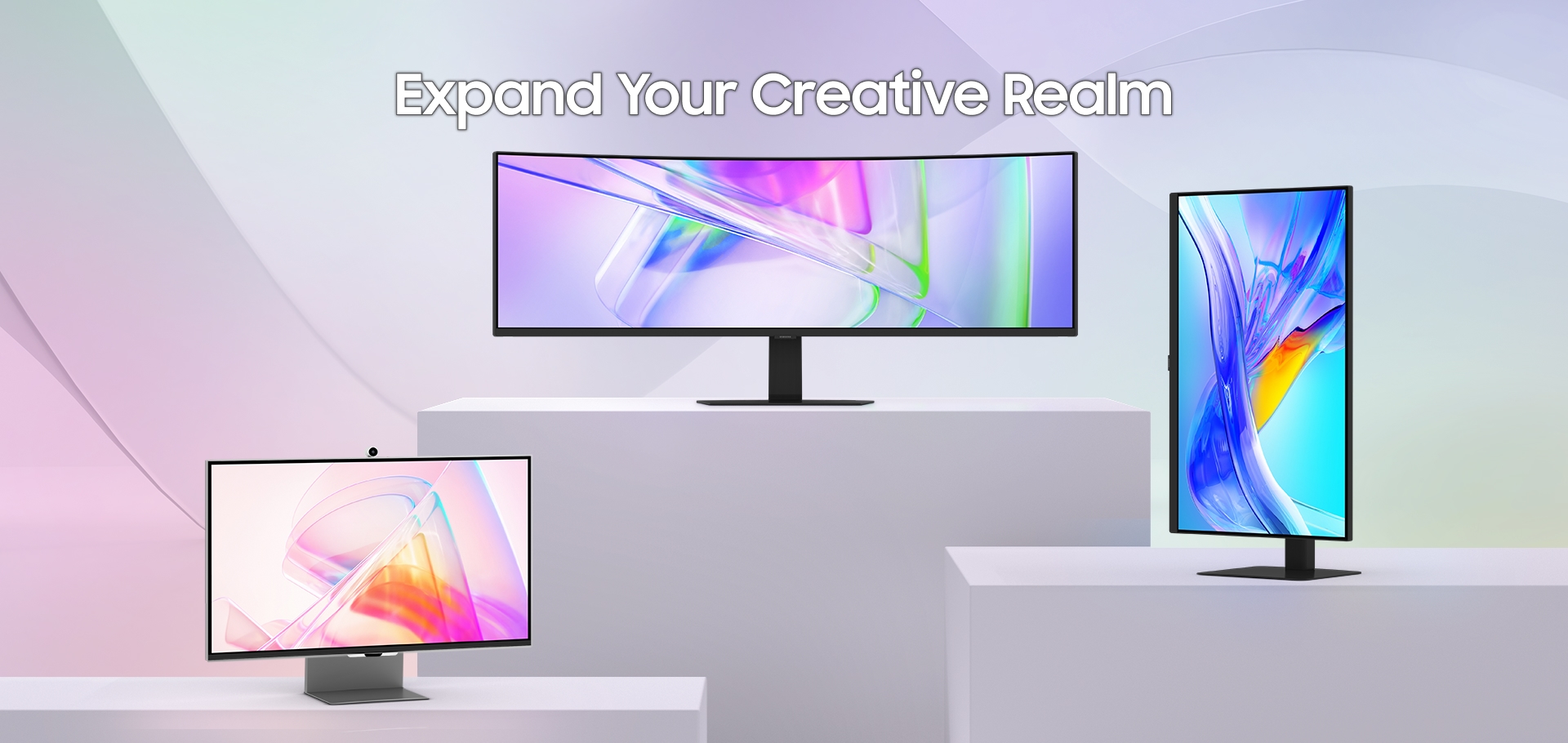 We zien drie monitoren op platforms met de tekst 'Expand Your Creative Realm' erboven.