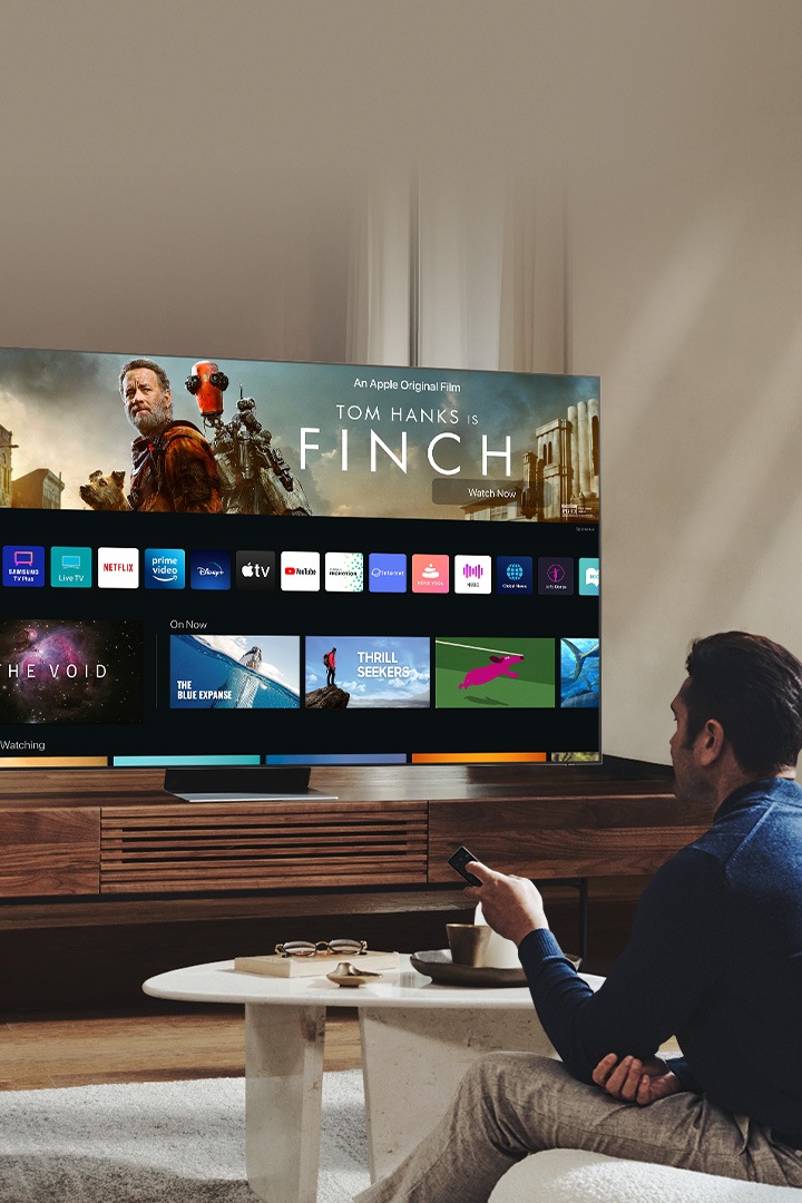 Een man kijkt naar de nieuwe Smart Hub UI op zijn Neo QLED in zijn woonkamer.