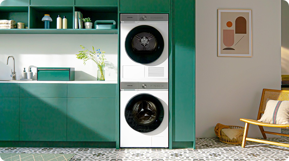 Een witten Bespoke AI™ Wasmachine en Droger zijn boven elkaar ingebouwd in een stijlvolle groene keuken.