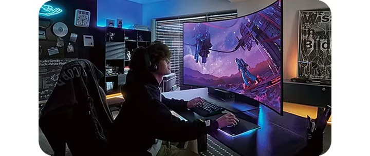 En man som spelar på en Samsung böjd spelmonitor när han sitter vid ett skrivbord