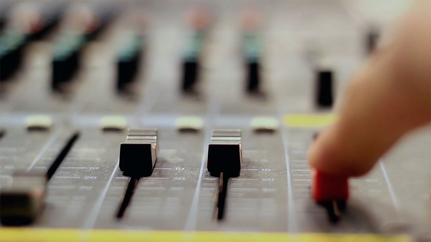 A hand is adjusting audio levels.