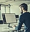 A man working in an office is looking at a computer screen.