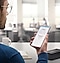A man holding up a Galaxy smartphone device is looking at a Samsung Knox app open.
