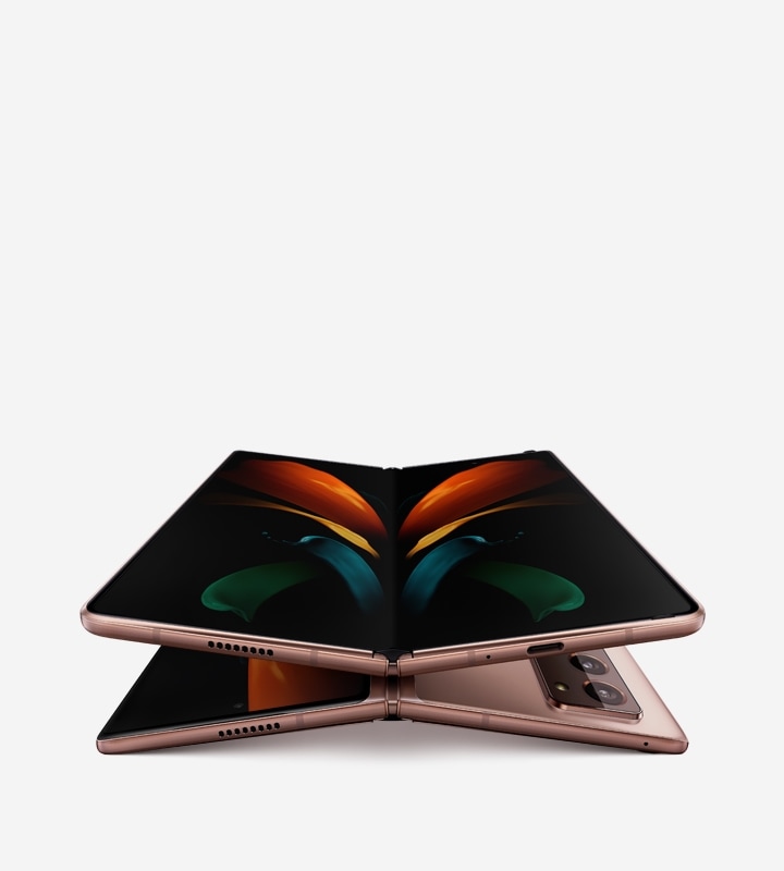 Two unfolded Galaxy Z Fold2 phones in Mystic Bronze, one laying face up and the other laying facedown. The one seen from the front is on top of the one seen laying facedown and has the butterfly wallpaper onscreen.