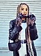 A woman with colorful braids, translucent gloves and a stylish black leather trenchcoat.