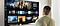 A person stands before a Smart TV, navigating through a myriad of content and OTT options.