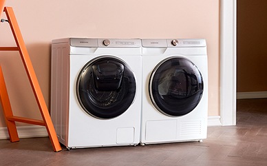 A woman who is leaning on the ladder is watching the Samsung washing machine and dryer.