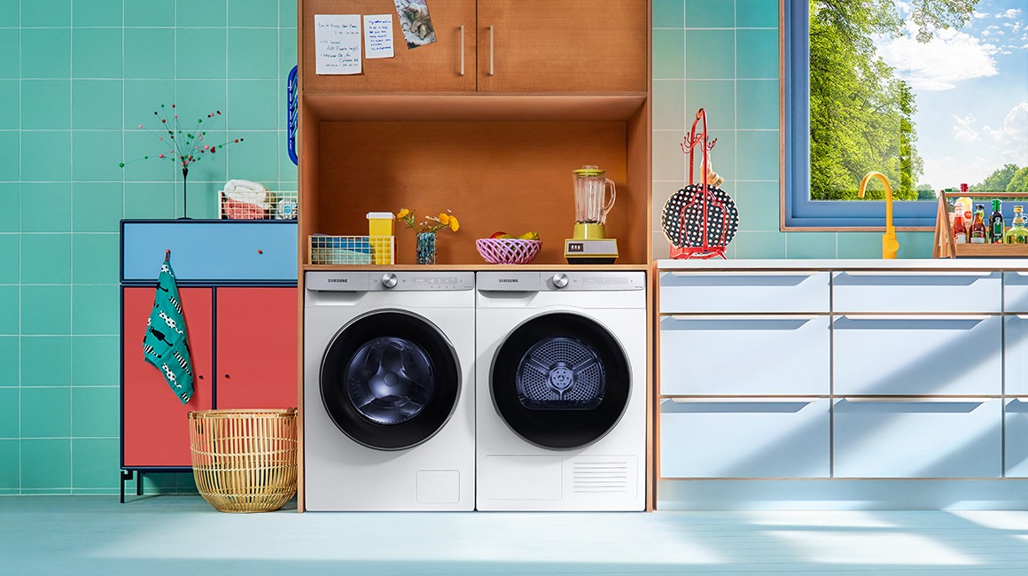 A man and a woman are taking a break in the living room where has a stackable white washer dryer from Samsung.