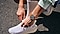 A close-up of a person tying shoelaces with Galaxy Watch Ultra on their left wrist