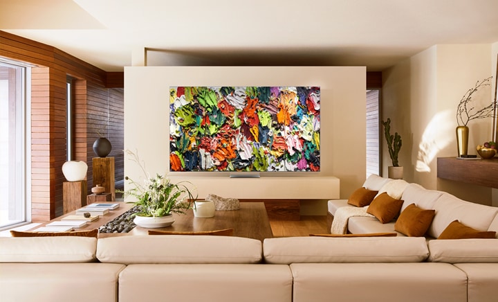 Nowoczesny salon z telewizorem Samsung wyświetlającym cyfrowe dzieło sztuki w intensywnych kolorach. Obraz przedstawia, jak technologia The Frame zmienia domową przestrzeń w cyfrową galerię sztuki dzięki współpracy z Art Basel i platformie Samsung Art Store.