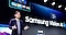 Um homem está de pé no palco em frente a um grande ecrã que diz “Samsung Vision AI”. Está a falar com a mão levantada num gesto a meio da fala.
