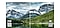 Para demostrar la necesidad de un televisor con pantalla de tamaño grande, una misma imagen de un paisaje montañoso se divide por el centro con una línea blanca para realizar una comparación de las resoluciones de pantalla FHD y 8K. La calidad de imagen de FHD se pixela debido a que tiene menos pixeles que 8K. Aparece una infografía de recuadros con casillas de gran tamaño y la palabra “FHD” arriba. La calidad de imagen 8K es mucho más clara y detallada debido a que tiene más pixeles que FHD. Aparece una infografía de recuadros con casillas de gran tamaño y la palabra “8K” arriba.