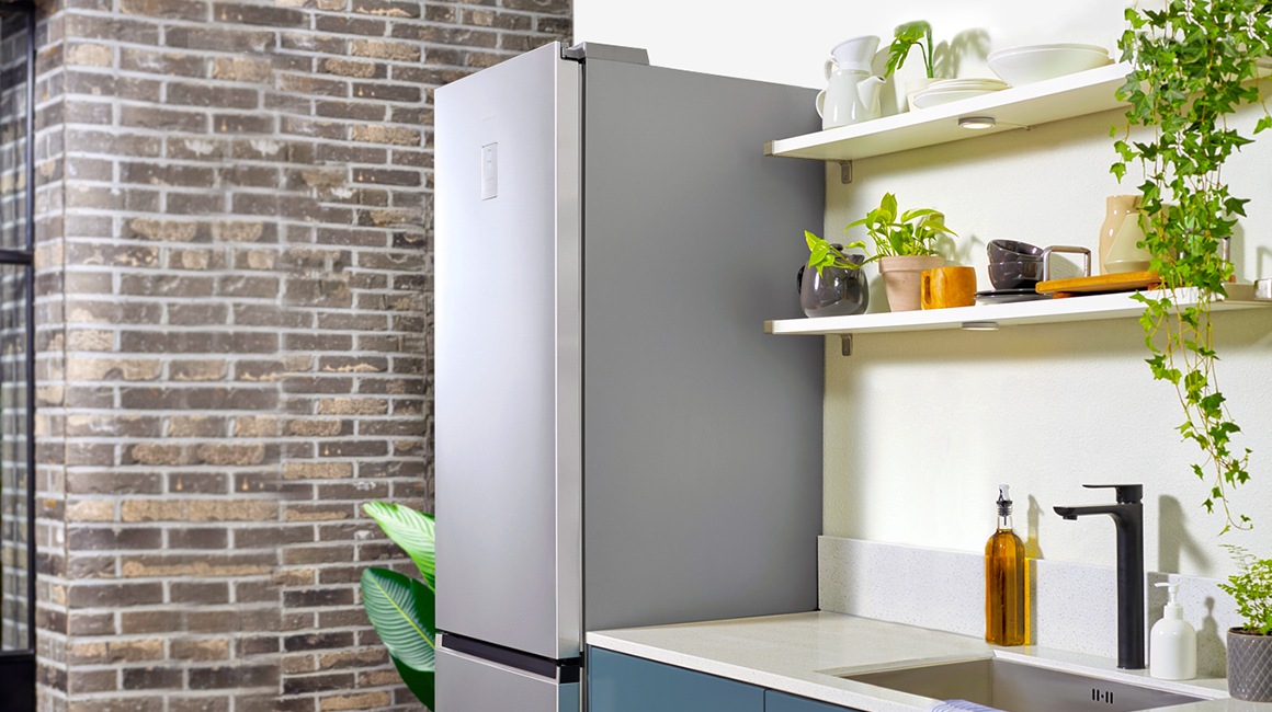 Un frigider Samsung RB7300T stă lângă dulapurile albastre cu chiuvetă, iar bucătăria prezintă un decor minimalist.