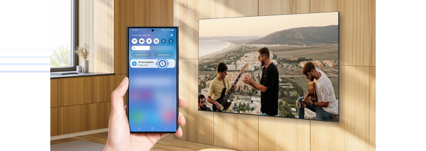Un televizor  Samsung Smart TV, pe perete, prezintă o scenă cu muzicieni cântând în aer liber. O mână ține un smartphone, în apropiere. Ecranul smartphone-ului indică detectarea unui televizor Neo QLED 8K, de 75 inci, în sufragerie, prin SmartThings. Pictograma pentru telecomandă este selectată. Ecranul smartphone-ului se transformă într-un ecran de telecomandă tactil. Când volumul este mărit pe telecomanda smartphone-ului, volumul difuzorului televizorului este crescut, ca răspuns. Apoi, smartphone-ul accesează ecranul de pornire al televizorului Samsung, unde este derulat în jos, pentru a afișa diferitele aplicații, servicii și opțiuni de difuzare în flux disponibile.