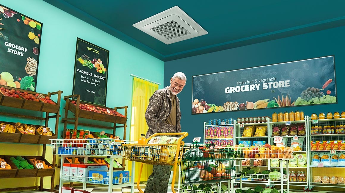 Мужчина толкает тележку, наполненную продуктами, под 4-сторонней кассетой в продуктовом магазине.