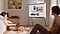 Man and woman playing with their dog in the bedroom in front of a Cloud White The Serif on a TV stand that is showing various photos from their mobile.