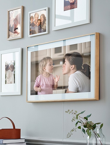 Рамка на стене с семейной фотографией среди других фоторамок.