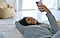 تظهر سيدة وهي مستلقية على الأرض ومبتسمة وتنظر إلى هاتف Galaxy S25 Ultra مع ظهور مقعد بين باج أصفر خلفها.