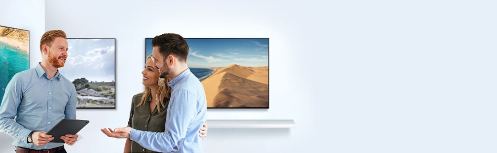 من أجل شراء TV جديد، يتحدث رجل وسيدة مع مندوب مبيعات بشأن خصائص TV في غرفة بمعرض أجهزة TV.