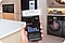 Smartphone seen with AI Energy Mode UI. Beside it  is a close-up of a washing machine dial, with a start  button and Cotton & Linen option next to it.