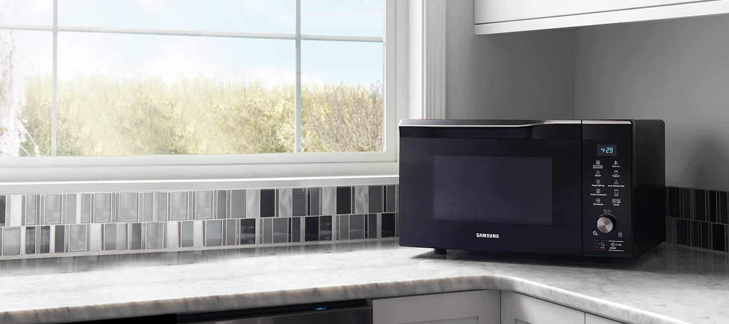 Black Samsung freestanding microwave on modern kitchen work surface.