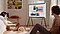Man and woman playing with their dog in the bedroom in front of a Cloud White The Serif on a TV stand that is showing various photos from their mobile.