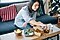 A woman in her living room sits on a couch while enjoying takeout food.