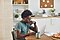 A man sits at a table in his kitchen, using a light grey Galaxy Book Pro laptop. He is also wearing a pair of black Galaxy Buds Pro in his ears.
