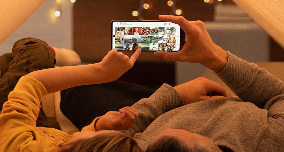 Father and daughter are looking at collection of photos saved on Galaxy A taken from day to day.