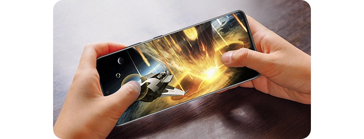 En mobiltelefon med spel visas. Den hålls vertikalt i två händer. På skärmen visas en propeller som avger? ljusgula och bruna strålar.