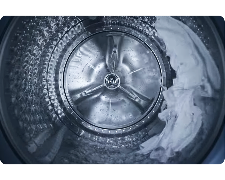 Interiör av tvättmaskin i aktion med vita kläder inuti