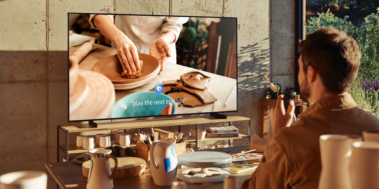 En man styr en Samsung TV med hjälp av röstassistenten Bixby