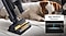 A Jet 85 with the Pet Tool+ cleans the sofa next to a dog. The brush's rubber nozzle and bristles are high-efficiency extractors, picking up all the pet hairs.