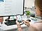 The mother is sitting at her office computer. Using her Samsung Galaxy S9, she is setting the washing cycle on her QuickDrive™ at home, using the Samsung Q-rator app. She smiles at being able to remotely control her washing machine.