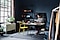 A wide shot of a man sitting at a desk, he is in a large room that seems to be his home office
