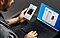 An over-the-shoulder shot of a man holding a Galaxy Note10 in his left hand and using the trackpad of a Galaxy Book S in his right, there are messages on both screens