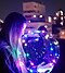 Poletna nočna fotografija ženske, ki drži svetleč LED balon, v ozadju pa sijejo bokeh luči