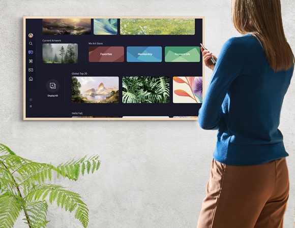 A woman using a remote to navigate the Samsung Art Store menu on The Frame TV, displaying various options.