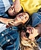 Three women laying down together and wearing earbuds.