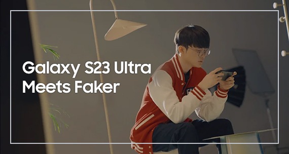 Faker joue à un jeu sur son Galaxy S23 Ultra, assis sur un tabouret entre une lampe et une table.