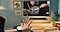 Uma TV The Frame está montada na parede da sala de estar, enquanto uma mão a usar um Galaxy Watch7 é vista a fazer um gesto para mostrar a funcionalidade de Gestos Universais para controlar a TV.