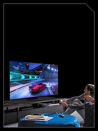 Two people are playing a car racing game via Samsung Gaming Hub on Samsung TV, using controllers.
