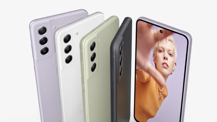 โทรศัพท์ Galaxy S21 FE 5G ห้าเครื่อง โดยมีโทรศัพท์สี่เครื่องสี Lavender, White, Olive และ Graphite หันหลังให้ และมีโทรศัพท์สี Lavender อีกเครื่องหันหน้าให้ โดยเครื่องที่หันด้านหน้าให้นั้นมีภาพของผู้หญิงคนหนึ่งที่ถ่ายเซลฟีแสดงอยู่ในหน้าจอ