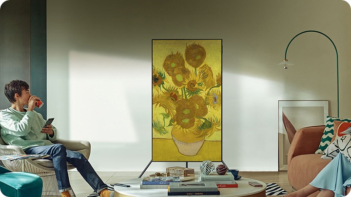 ผู้ชายคนหนึ่งชม TV ที่ติดตั้งอยู่กับ Auto Rotating Stand TV แสดงผลภาพวาดของดอกไม้อยู่ในโหมดแนวตั้ง