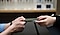 Closeup of the hands of a Galaxy Consultant handing a repaired phone in a case to the hands of a client across the counter