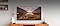 At the center of the living room, a large Samsung TV is hung up on the wall displaying a majestic view of nature. Below it lies a TV stand and various interior decorations.