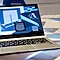 A laptop computer displaying a blue screen, positioned on a flat surface.