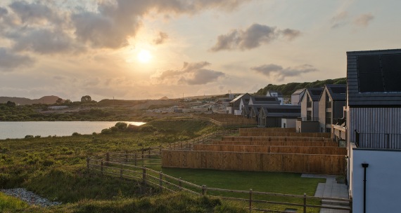 A picturesque landscape featuring homes adjacent to a calm lake, with trees and nature enhancing the serene atmosphere.